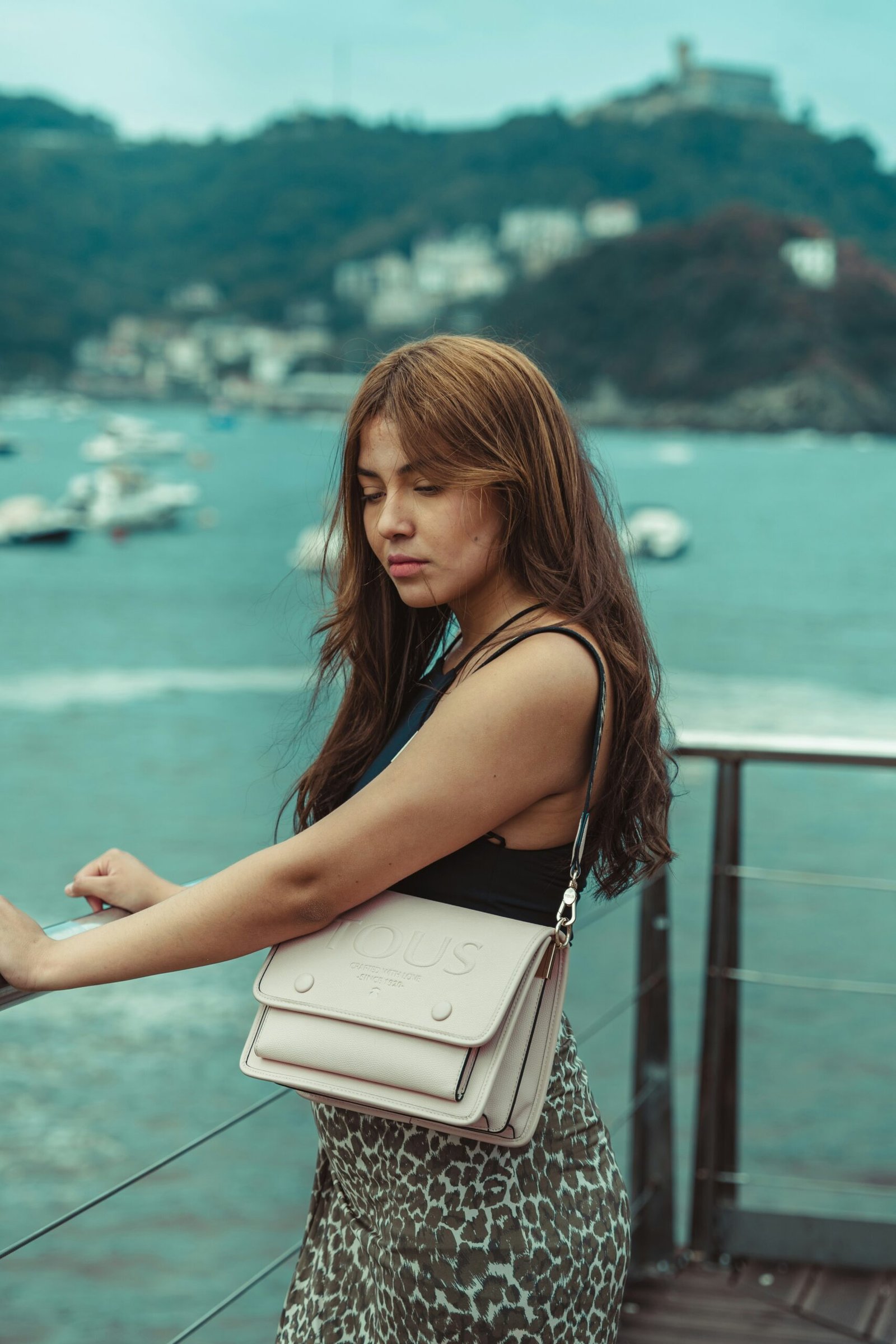 a woman holding a white purse on top of a pier